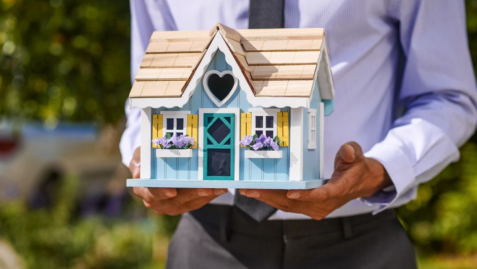 Poslovni čovjek drži detaljan minijaturni model kuće